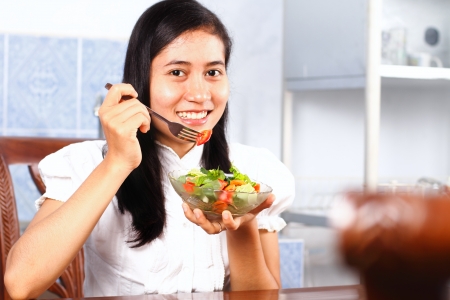 Young woman eating vegetable saladの写真素材