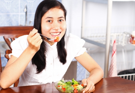Young woman eating vegetable saladの写真素材