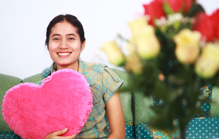 Beautiful young woman holding pink heart smiling look you cameraの写真素材