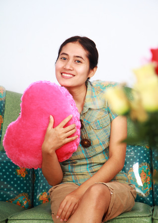 Vertical image beautiful young woman holding pink heart の写真素材