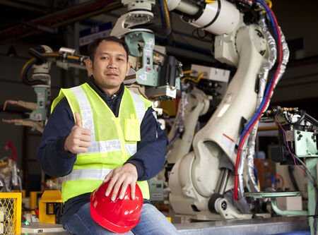 Factory worker relaxing  break beside robot machineの写真素材