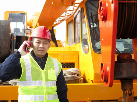 Construction worker calling with hand phone on crane truckの写真素材