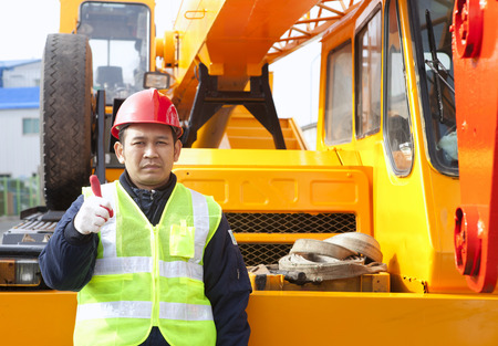 Construction worker giving thumb up with heavy equipment の写真素材