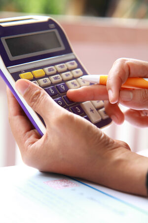 Close-up photo of business woman hand accounting financial report. Female hand with pen and calculator analyzing financial dataの写真素材