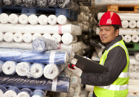 Textile factory foreman checking raw material fabrics in warehouseの写真素材
