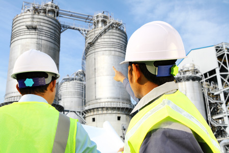 Two engineer oil gas refinery discussion under storage tank industryの写真素材