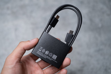 Male hand holding black USB cable to charge a smartphoneのeditorial素材