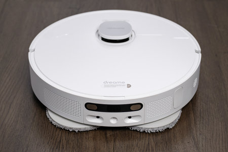 New white robot vacuum cleaner on wooden floor, close-up.のeditorial素材