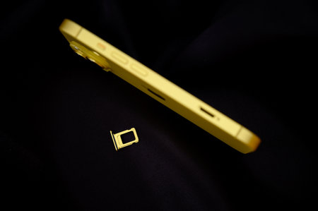 Close up of a yellow mobile phone on a black fabric background.