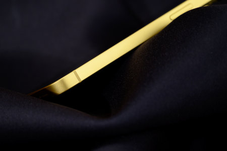 Golden mobile phone on black satin fabric background. Close up.のeditorial素材