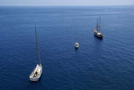 3 sail boats in blue water, forming a diagonal. Photo taken in Aeolian Island, Sicily, Italy.