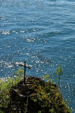 Christian cross on a rock looking at the lakeの写真素材