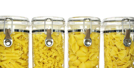 Various shapes of pasta in jars: fusilli (spirals), penne, farfalle (bow tie), conchiglie (shells) on white backgroundの写真素材