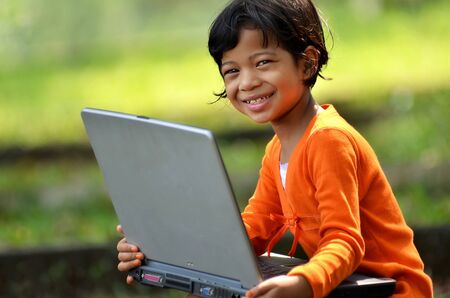 Cute girl dress in orange playing with laptop computerの写真素材