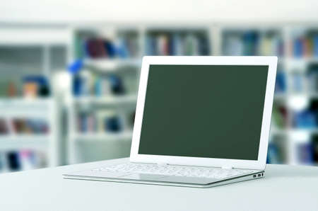 Elegant white laptop template with blurry  bookshelf as background  You can change the laptop screen...