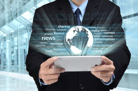 A businessman accessing internet and information technology via tablet   gadget in his handの写真素材