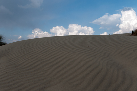 Black shadow on the sand dunes and cloudsの写真素材