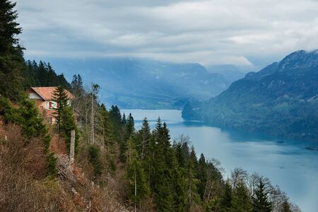 Small house on the hill beside the river near deep moutain valley in cloudy day.の写真素材