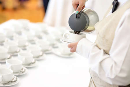 Hotel breakfast service - waitress pouring coffee for guestの写真素材