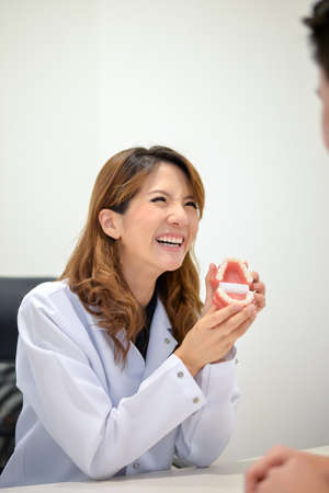 {Chinese) Female dentist show denture with big smile to patient