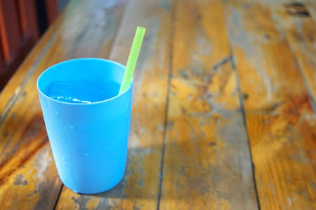 blue ice water plastic glass on wooden table