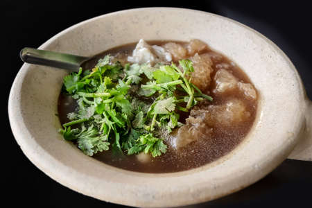 Chinese favorite street food soup , fish maw soup with crab meat and shitake topped with corianderの写真素材