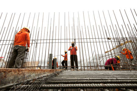 Construction workers working on steel rods used to reinforce concreteの写真素材
