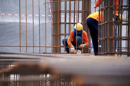 Construction workers working on steel rods used to reinforce concreteの写真素材