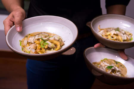 Waiter serve yellow spaghetti with black truffle with busy handの写真素材