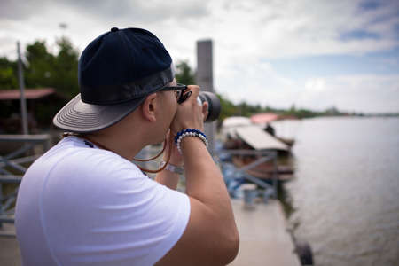 Back view of man take a picture near ther riverの写真素材