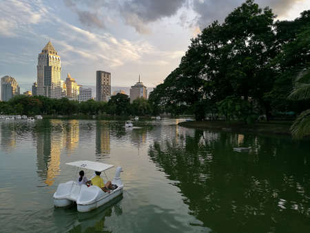 Bangkok Thailand August 1 , 2016 - People relaxing with swan Pedal boat in the pond of the park inear the urban skyscrapersの写真素材