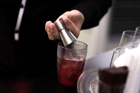 Bartender pouring cocktail in glasses
