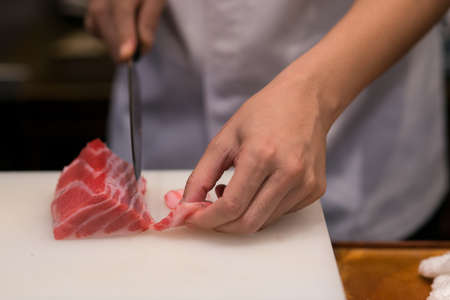 Japanese chef is neatly cutting on fine part of yellow fine tuna to make nigiri maguro sushiの写真素材