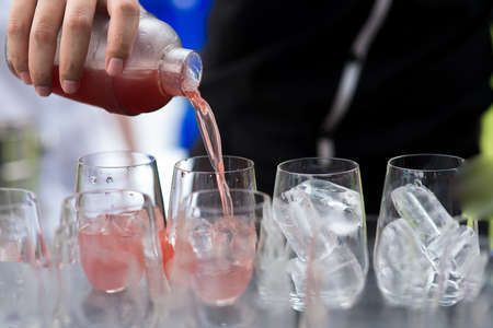 Bartender pouring cocktail in glassesの写真素材