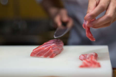 Japanese chef is neatly cutting on fine part of yellow fine tuna to make nigiri maguro sushiの写真素材