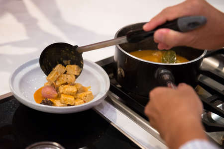 chef pouring chicken to curry bowlの写真素材