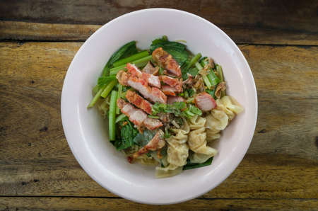 Top view bowl of egg noodles with roast pork, dumpling and vegetableの写真素材