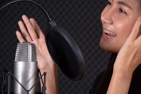 Asian lady show her talent by singing in music studio record roomの写真素材