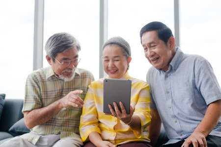 group of retired behind tablet sitting on couch smiling with their families on mobile device