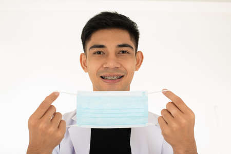 asian man in white uniform prepare to wear surgical maskの写真素材
