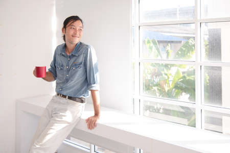 asian guy with red cup of coffeeの写真素材