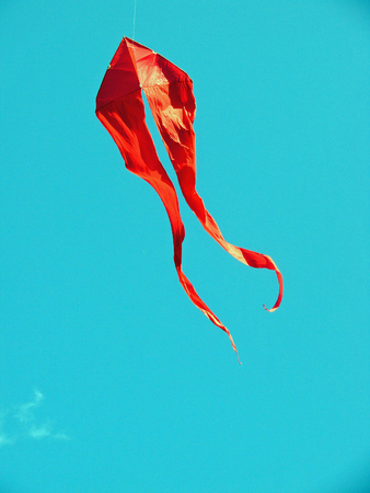 A bright red kite flying on a clear dayの写真素材