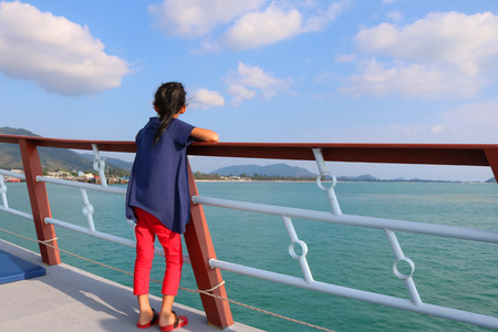A girl stands on a boat near the pier.の写真素材