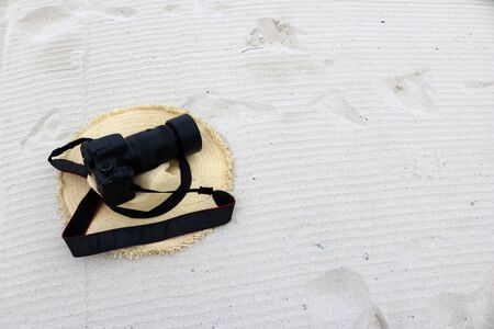 Camera rests on a woven hat on the beach.