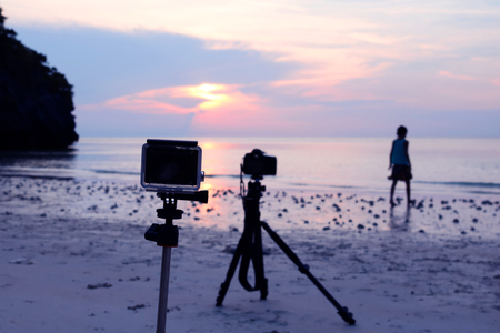 camera and tripod at the beach with a background image of girl with the sunset.の写真素材