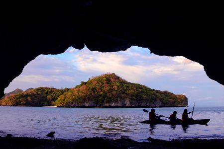 Family paddling a kayak through the cave by the sea.の写真素材