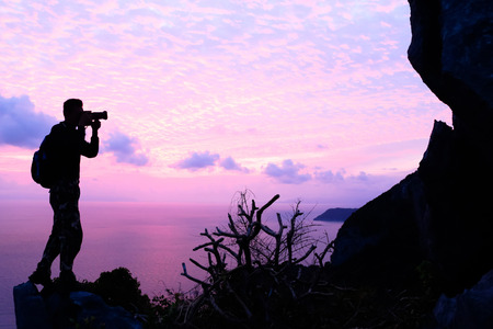 Man with camera and purple sky before sunrise on the mountain.の写真素材