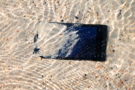 The Phone  camera fall to the water on the beach.の写真素材