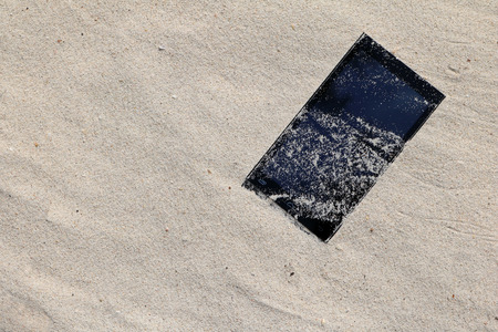 Mobile phones in the sand on the beach.の写真素材