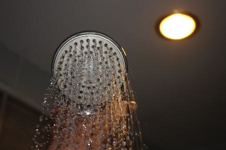 Water flowing from the shower with the reflected light from the lamp.の写真素材